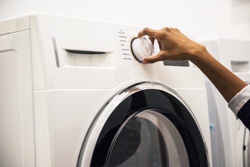 person-turning-dial-on-front-loading-washing-machine